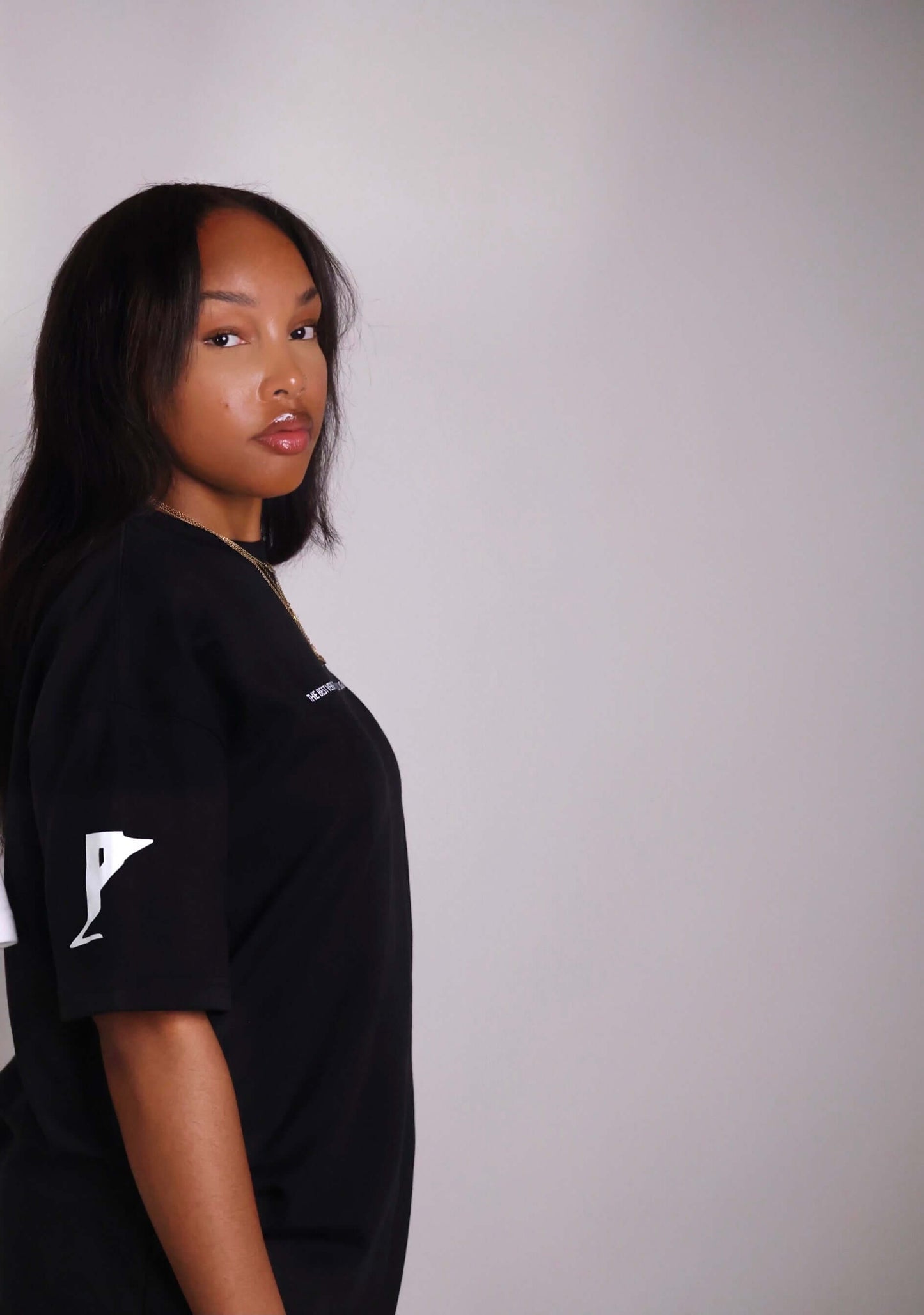 Person wearing PC FUSION-SCRIPT STRIVE AHEAD TEE, a black unisex t-shirt with vinyl print on arm, showcasing an empowering clothing brand.