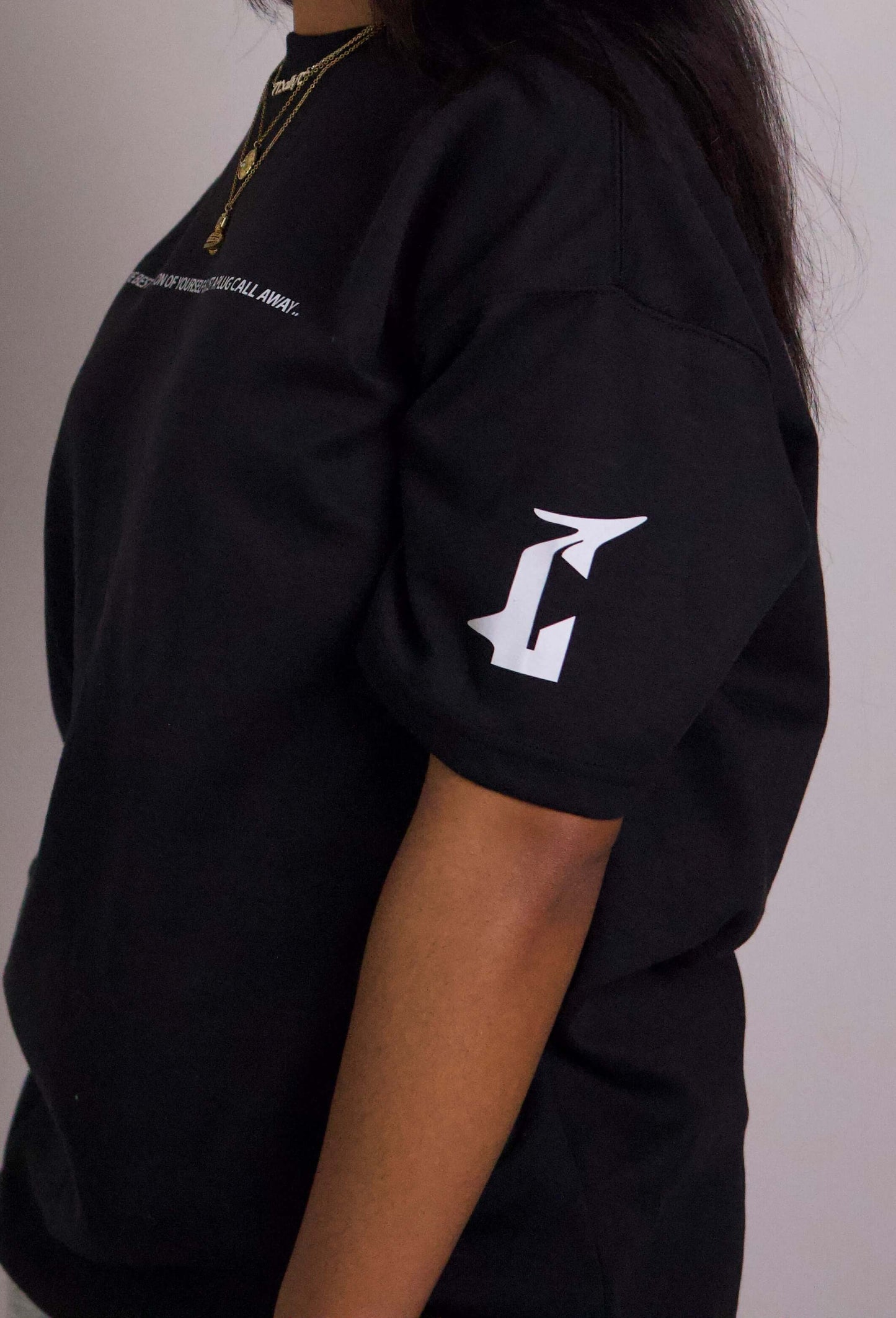 Unisex black boxy drop sleeve tee with vinyl print on arm, worn by fashion-forward individual from empowering clothing brand.