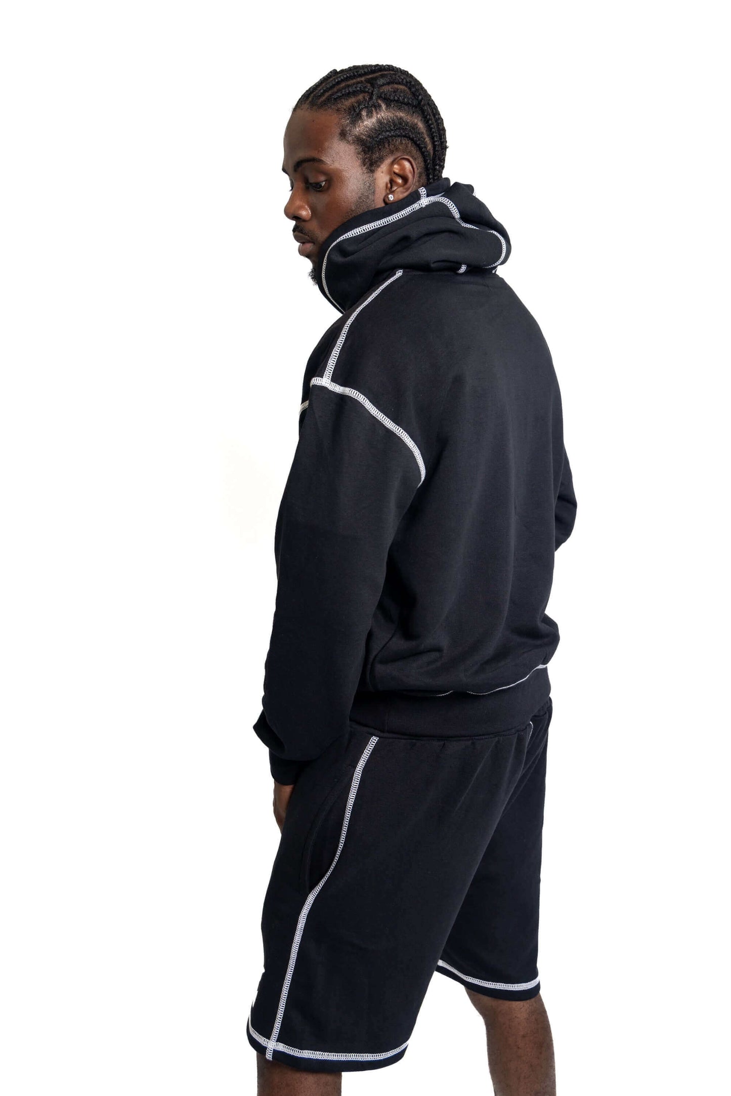 Model wearing contrast-stitch shorts set featuring a black hoodie and shorts with white stitching.